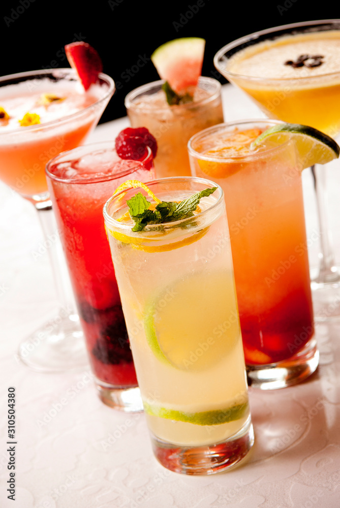 Colorful cocktail drinks with garnishes on white table Colorful cocktail drinks with garnishes on white table