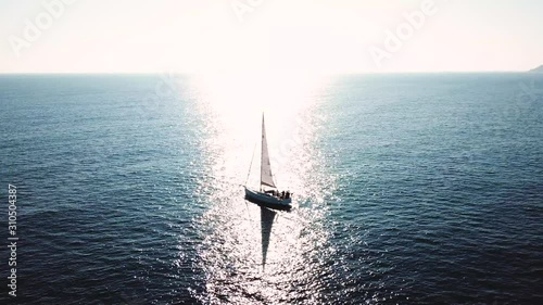 Turkey, Mediterranean sea - 27.10.2019: Silhouette of a yacht under sail opposite the reflection of the sun from the water photo