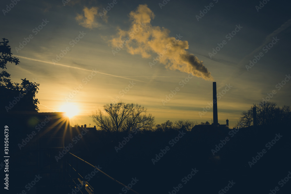 Image of industrial chimney and smoke during sunrise