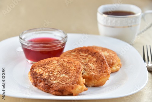 Fritters on a white plate with cherry sauce