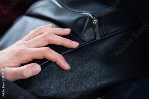  woman hand resting on a black purse