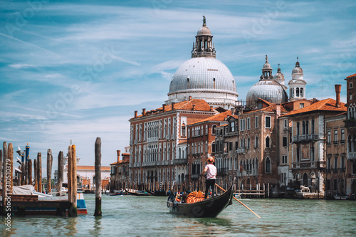 Fototapeta Naklejka Na Ścianę i Meble -  Traditional Gondola and gondolier on Canal Grande with Basilica di Santa Maria della Salute in the background in Venice, Italy. Summer vacation city trip