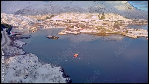 drone view of a fishing boat surrounded by birds flying above it in a Norwegian fjord