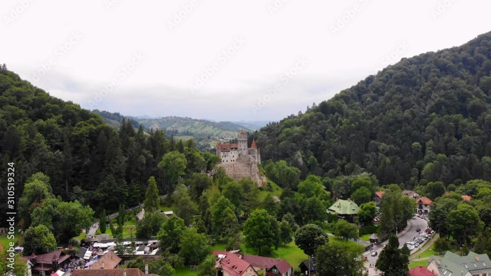 aero. panoramic view of the ancient Bran castle on a hill , Dracula Castle, Transylvania, Brasov, Romania. at the foot of the castle there is a small town. summer day aero. panoramic view of the ancient Bran castle on a hill , Dracula Castle, Transylvania, Brasov, Romania. at the foot of the castle there is a small town. summer day