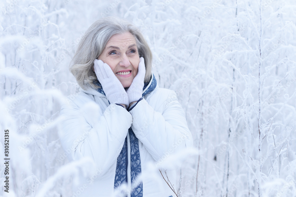 Portrait of happy beautiful senior woman posing in snowy winter park