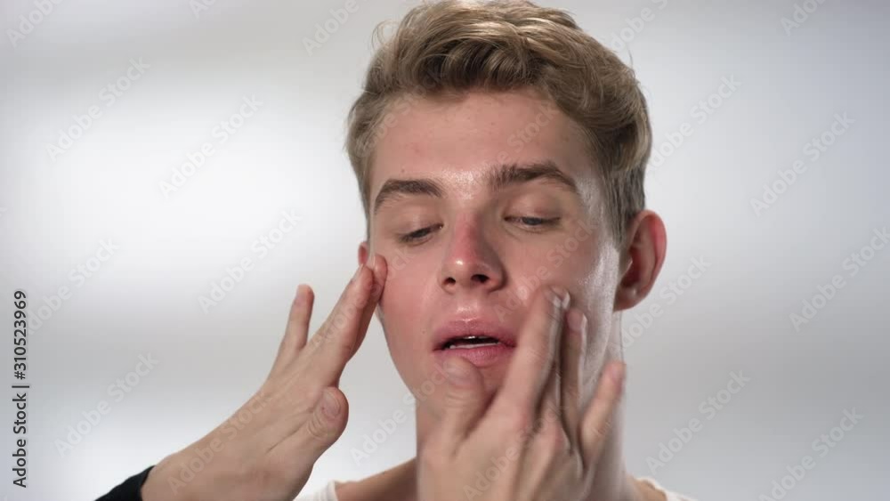 Time lapse of male skillful visagiste applying organic serum on face of pretty Caucasian man with his fingers and then cleaning skin with napkin Time lapse of male skillful visagiste applying organic serum on face of pretty Caucasian man with his fingers and then cleaning skin with napkin