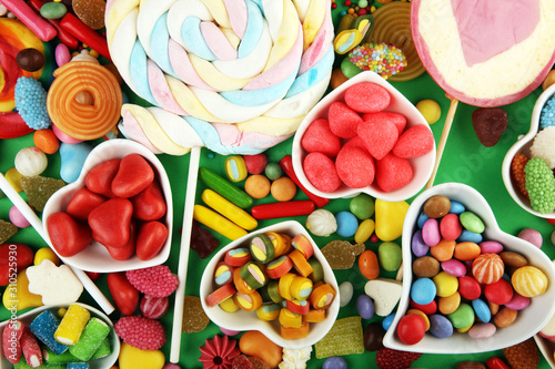candies with jelly and sugar. colorful array of different childs sweets and treats on green background