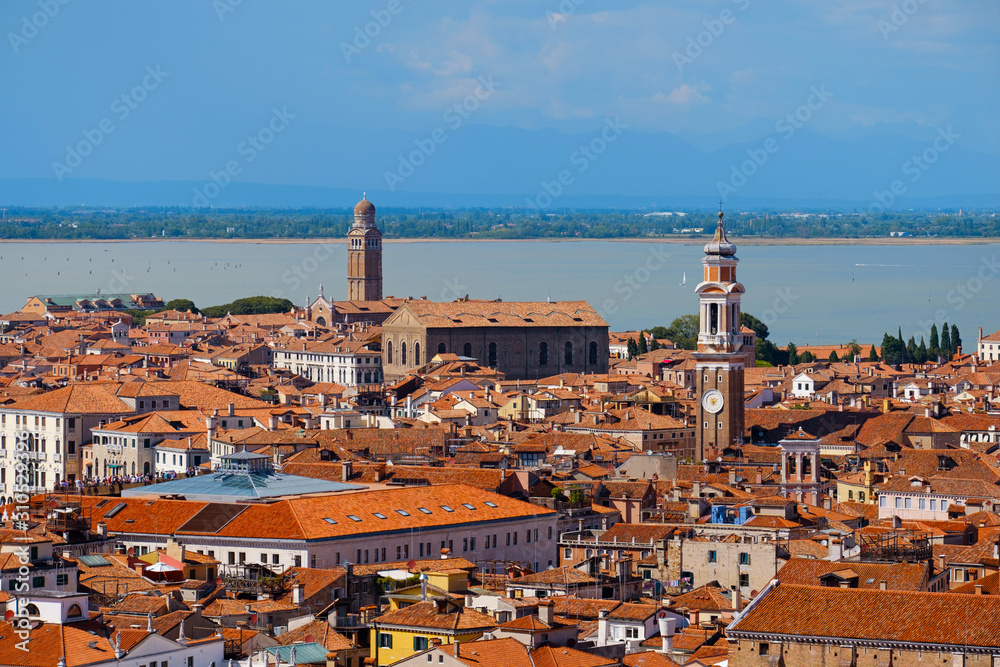 Aerial view of Venice, Italy. Top view of Venice from the Campanile tower of Saint Mark's Cathedral (Basilica di San Marco) and Doges' Palace. Cityscape panorama of Italian houses with red roofs.