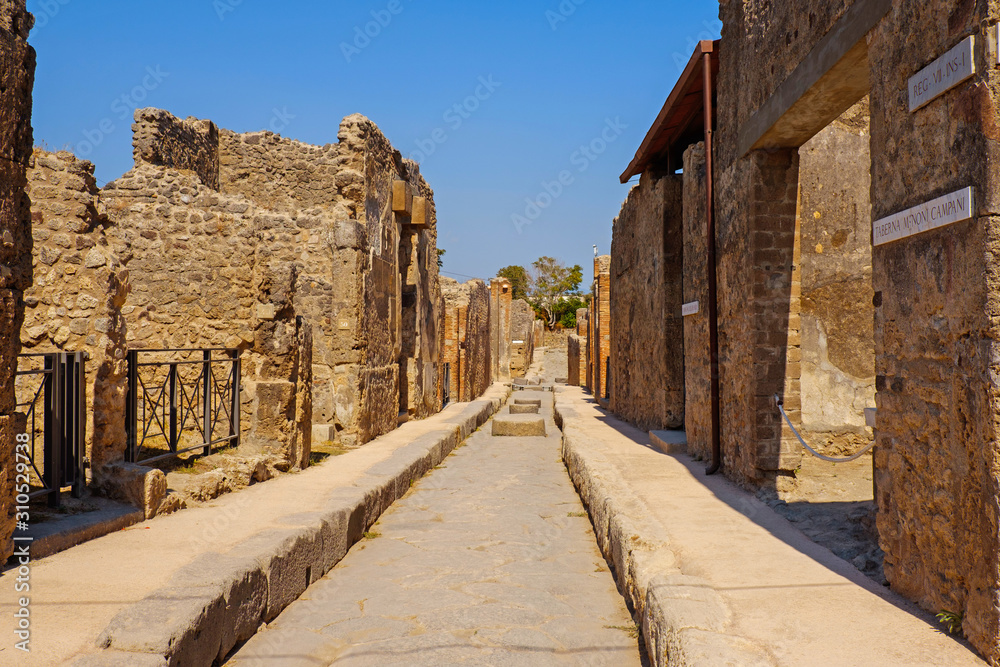 Ancient city Pompeii with arches, forum, columns, houses and streets. Ruins of Roman city destroyed by the eruption of volcano, Mount Vesuvius. Naples, Italy. Popular Italian travel destination.