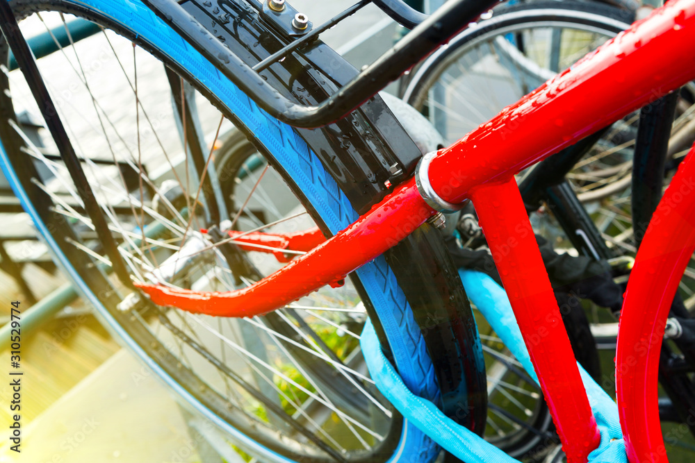 Close up of a modern red bicycle with blue tires parked in the streets of Amsterdam in the morning