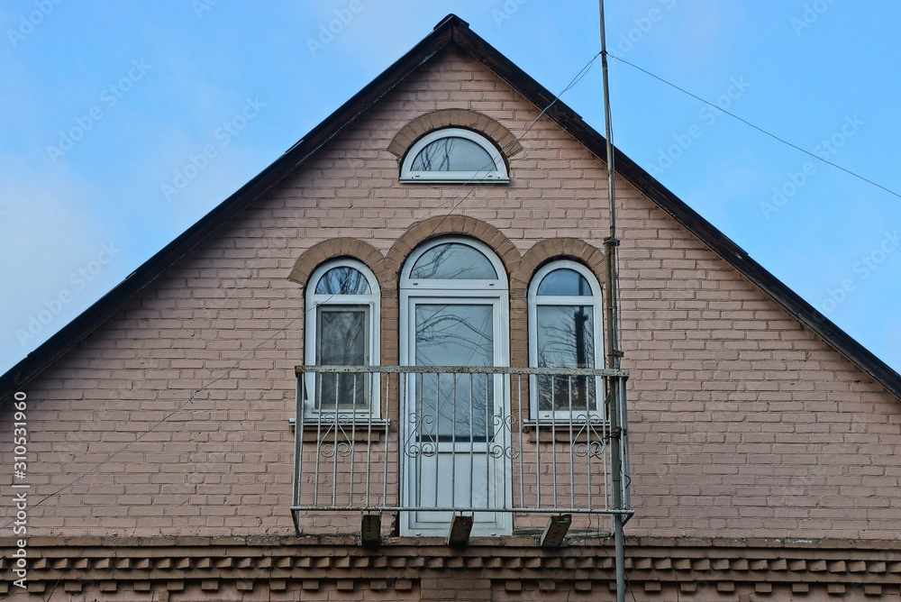 brown brick loft with iron balcony against a blue sky