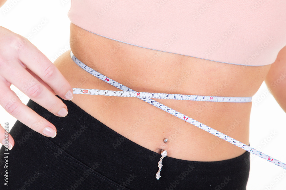 close-up slim woman measuring waist using measuring tape isolated over white background wearing sporty wear