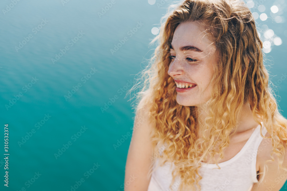 blonde laughs happily against the backdrop of the ocean