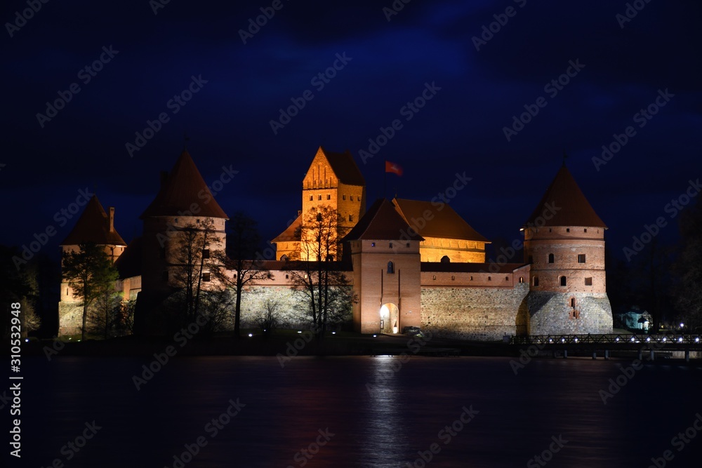 Medieval castle of Trakai, Vilnius, Lithuania, Eastern Europe, located between beautiful lakes and nature with wooden bridge and lights, at night