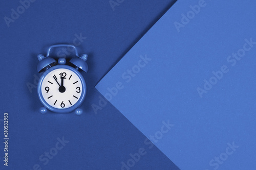 Blue alarm clock on trendy toned background.