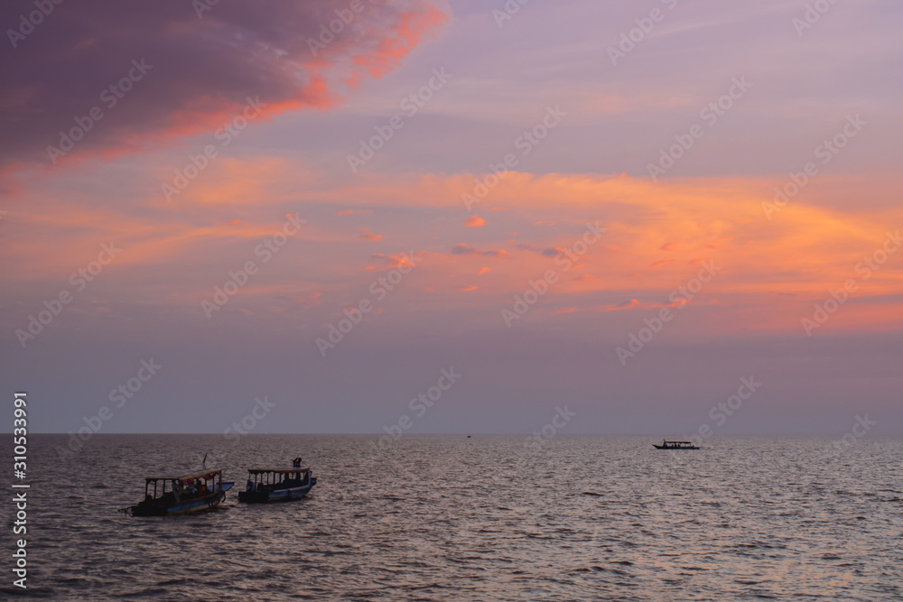 Boats on a wide sea during beautiful pink sunset in Asia