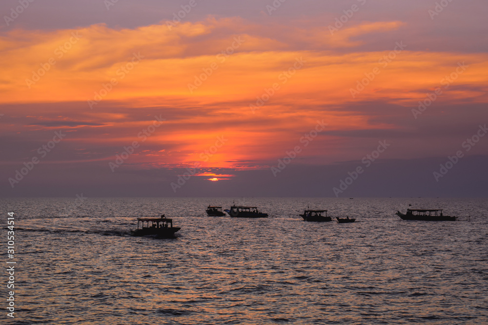 Group of boats on a wide sea during beautiful pink sunset in Asia