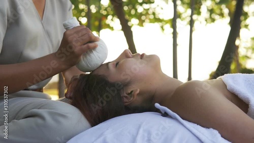 Young Asian Woman relaxing having head massage outdoor. Asian male laying in bed. concept massage at spa.