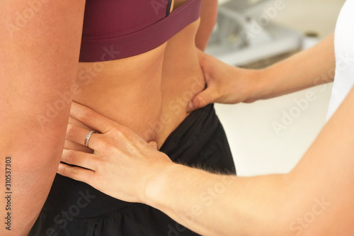 Woman patient at physiotherapy session  detail on therapist hands touching muscles on her back