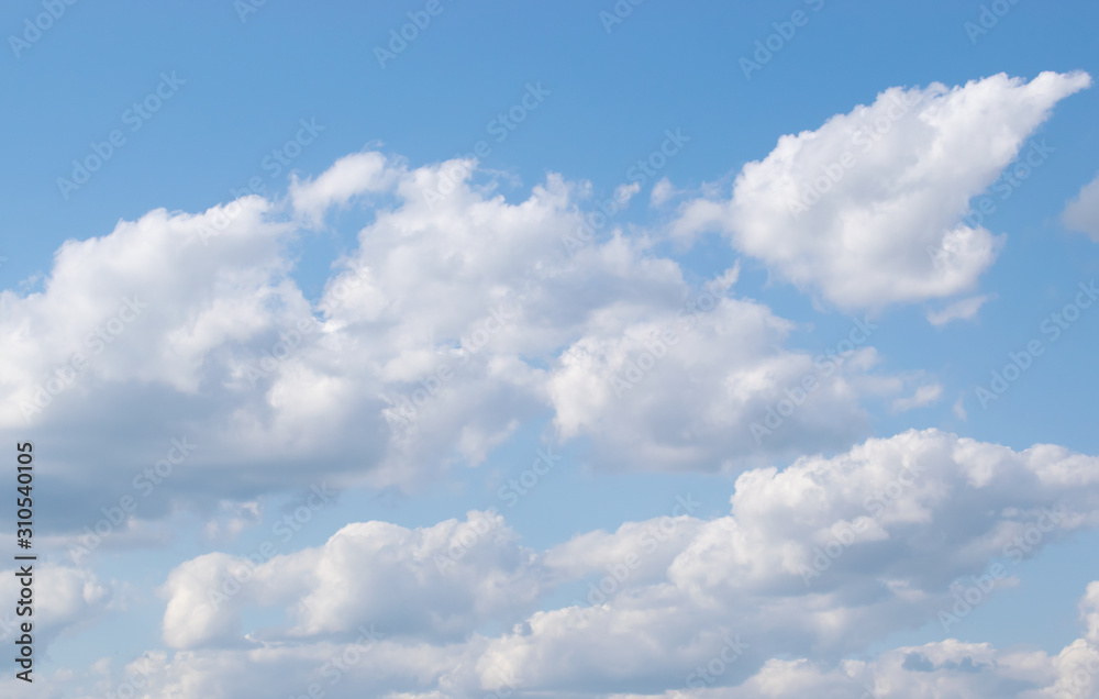 Beautiful white cumulus clouds slowly floating against a clear blue sky Beautiful white cumulus clouds slowly floating against a clear blue sky
