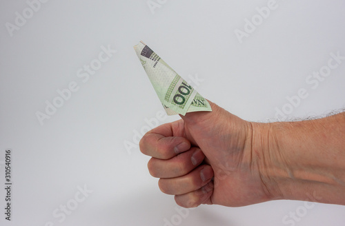 100 Polish zloty bill rolled into cone shape  and stuck on a thumb in a thumbs up gesture