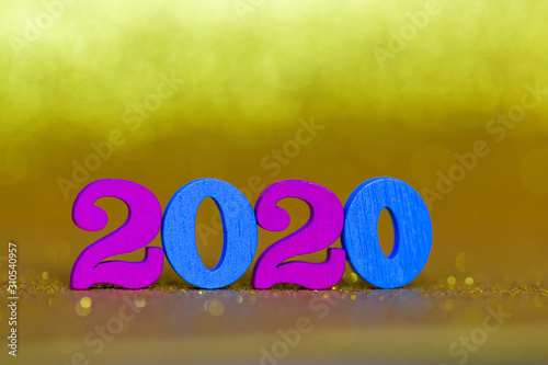 Wooden purple and blue numbers 2020 on a golden blurry background. Shiny festive Christmas gold background. Free space for text