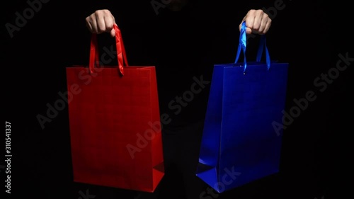 maie hands holding a colorful package on a black background. copy space. photo