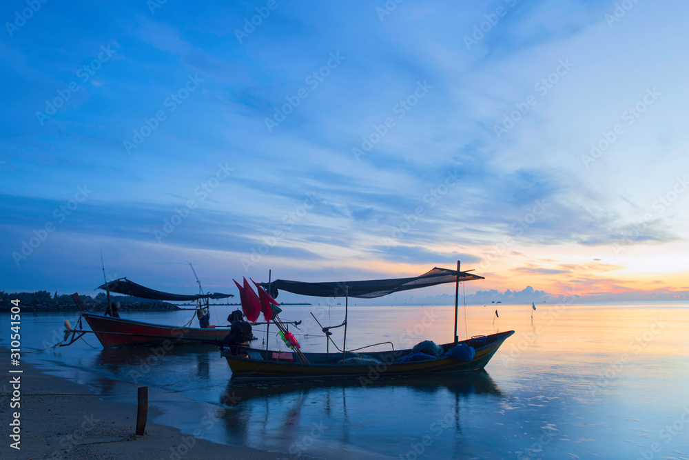 Two wooden fishing boats moored on the beach in the morning under the blue sky. Two wooden fishing boats moored on the beach in the morning under the blue sky.