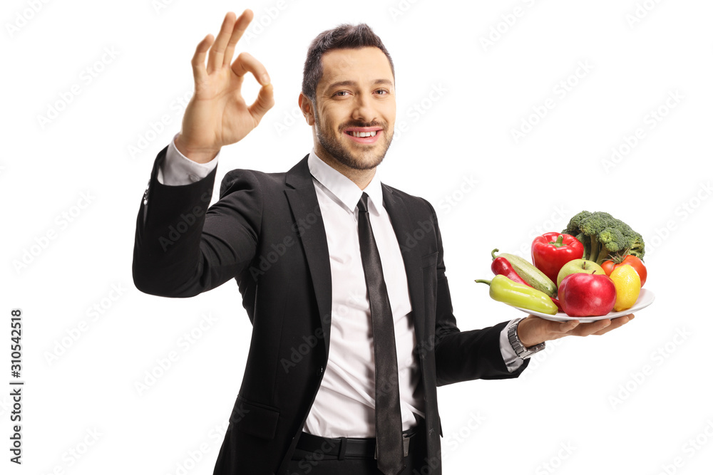 Businessman with a plate of fruits and vegetables gesturing a sign for perfect with hand Businessman with a plate of fruits and vegetables gesturing a sign for perfect with hand