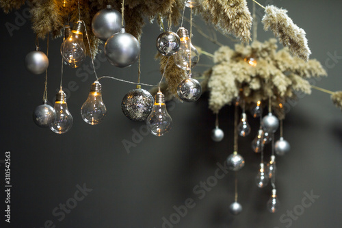 A decorative reed clouds hanging from above with a Christmas decor and a garland of light bulbs, Christmas or New Year concept