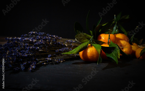 still life with lavender and tangerines in a dark key. composition of flowers and fruits for decoration cards.