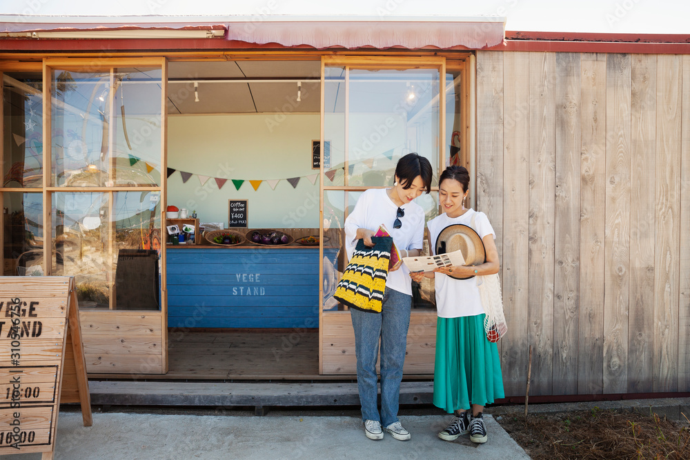 Two smiling Japanese women standing outside a farm shop. Two smiling Japanese women standing outside a farm shop.