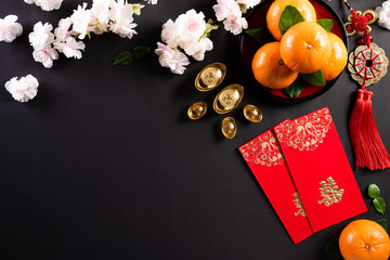 Chinese new year festival decorations pow or red packet, orange and gold ingots or golden lump on a black background. Chinese characters FU means fortune good luck, wealth, money flow.