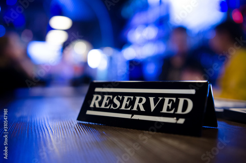 Restaurant reserved table sign standing on wooden table in bar