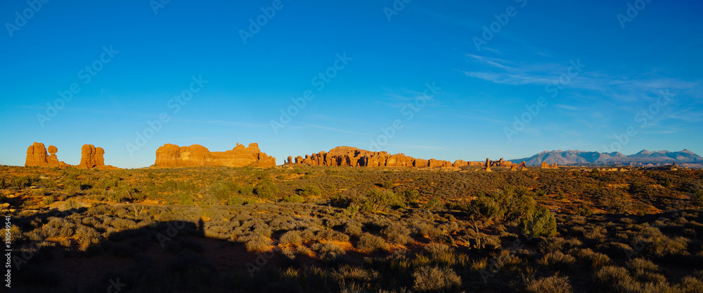 A long panorama sunset view of the series of rock formations that houses the North and South Window Arches, Double Arch, Balancing Rock, and more.