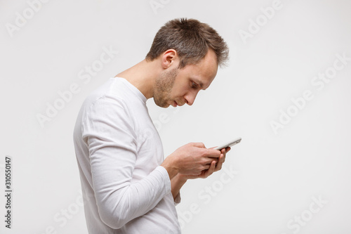 Close up portrait of man looking and using smart phone with scoliosis, side view, isolated on gray background. Rachiocampsis, kyphosis curvature of neck, Incorrect posture, ,  orthopedics concept photo