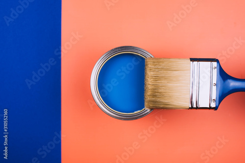 Fototapeta Naklejka Na Ścianę i Meble -  Brush on open can of blue paint on coral and blue background. Concept of changing color of the year.