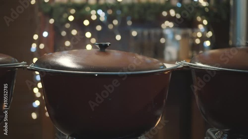 huge pans with hot mulled wine at christmas festive. street shop with traditional mulled wine. Close-up hot wine pan in evening at Christmas market. Street food, mulled wine boiled in tub on fire photo