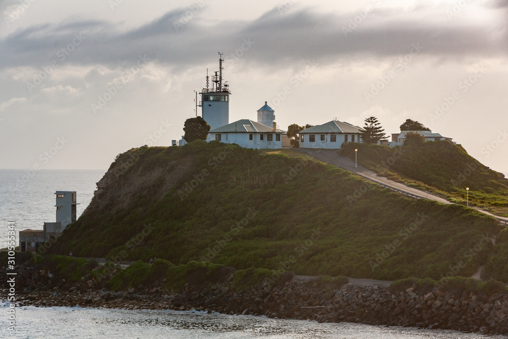 Nobbys Lighthouse building on its hill under gray cloudscape, Newcastle, Australia.