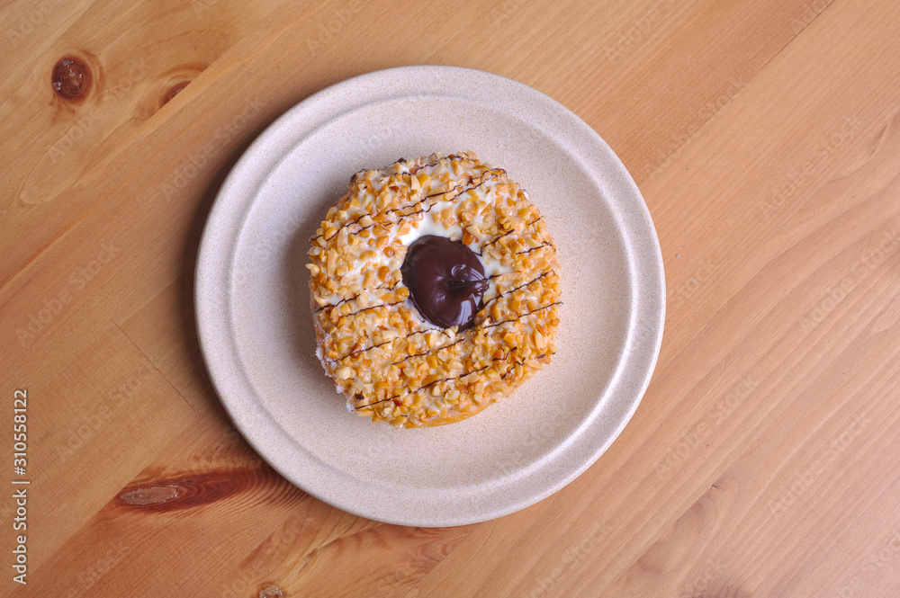 A donut with peanut as a topping on top of wooden table. A donut with peanut as a topping on top of wooden table.