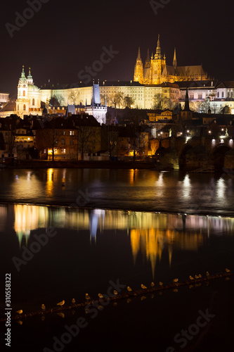 Night winter Prague Lesser Town with the gothic Castle and Charles Bridge above the River Vltava, Czech Republic