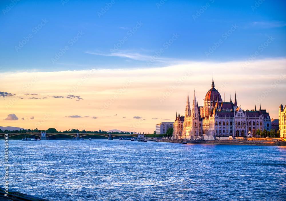 Obraz premium Budynek parlamentu węgierskiego położony nad Dunajem w Budapeszcie na Węgrzech o zachodzie słońca.