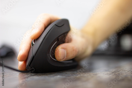 man’s hand uses a vertical ergonomic computer mouse-joystick. photo