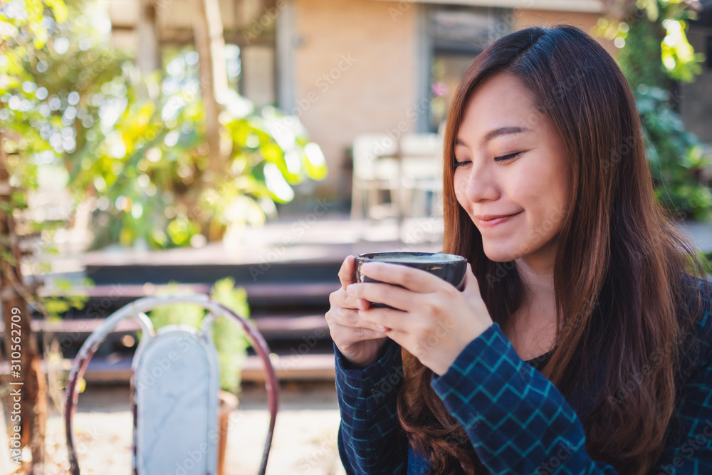 Closeup image of a beautiful asian woman holding a cup of hot coffee to drink Closeup image of a beautiful asian woman holding a cup of hot coffee to drink