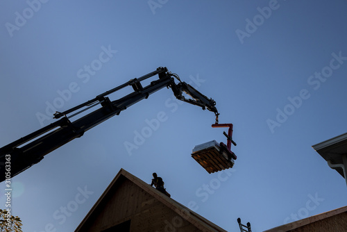 Boom truck forklift in the roof a new home is used to roof trusses to a house extension