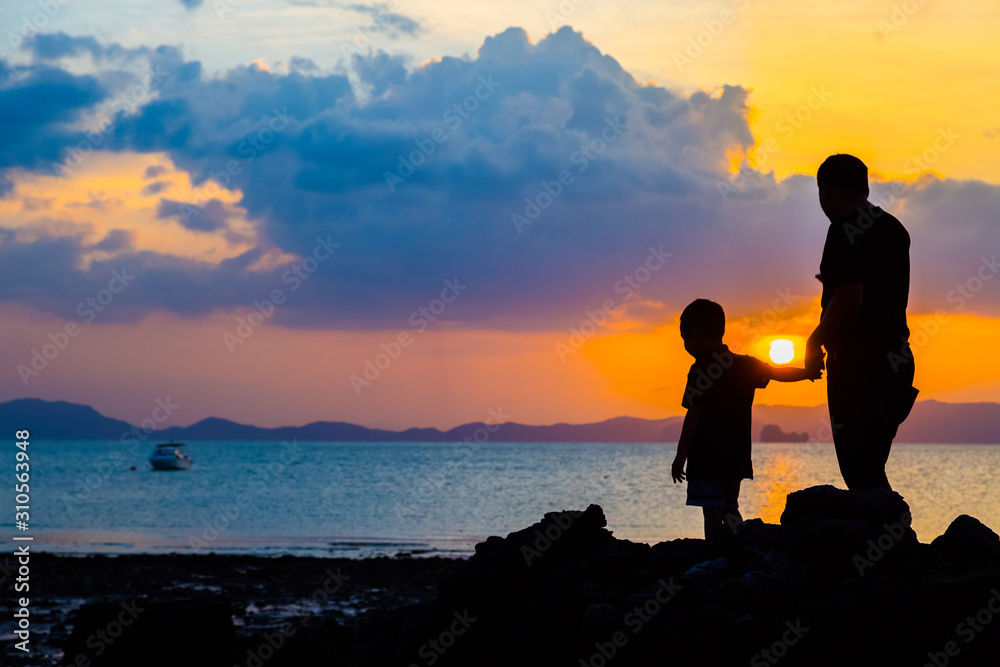 Silhouette image of father and son at the beach