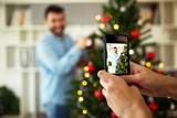 Girl photographing man while he decorating Christmas tree