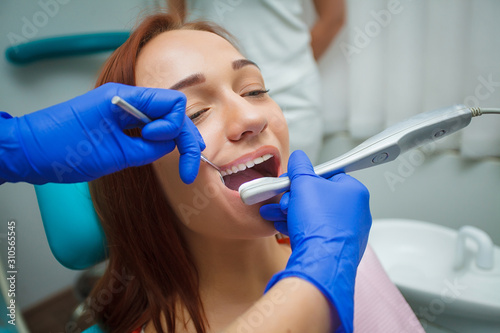 Young beautiful woman with beautiful white teeth sitting on a dental chair. Dentist examining a patients teeth in the dentists chair at the dental clinic