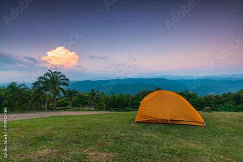 The orange tent of traveler on the cliff in the evening.