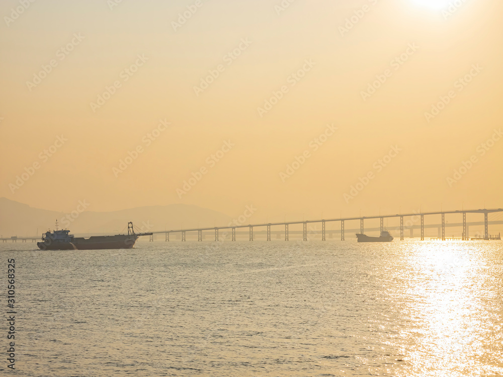 Sunset view of the cargo ship and old Macau Taipa bridge